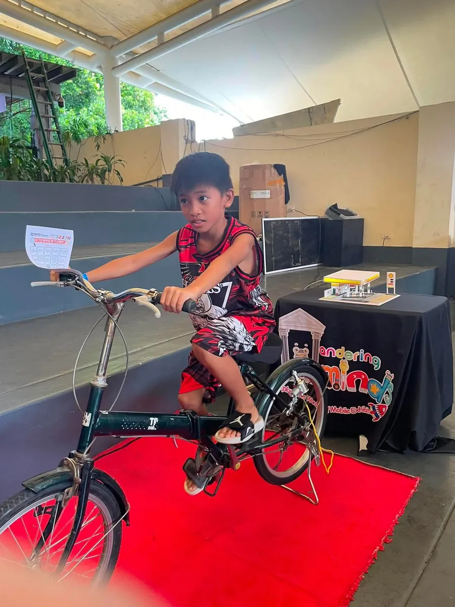 A young visitor powering a renewable energy model by bicycle