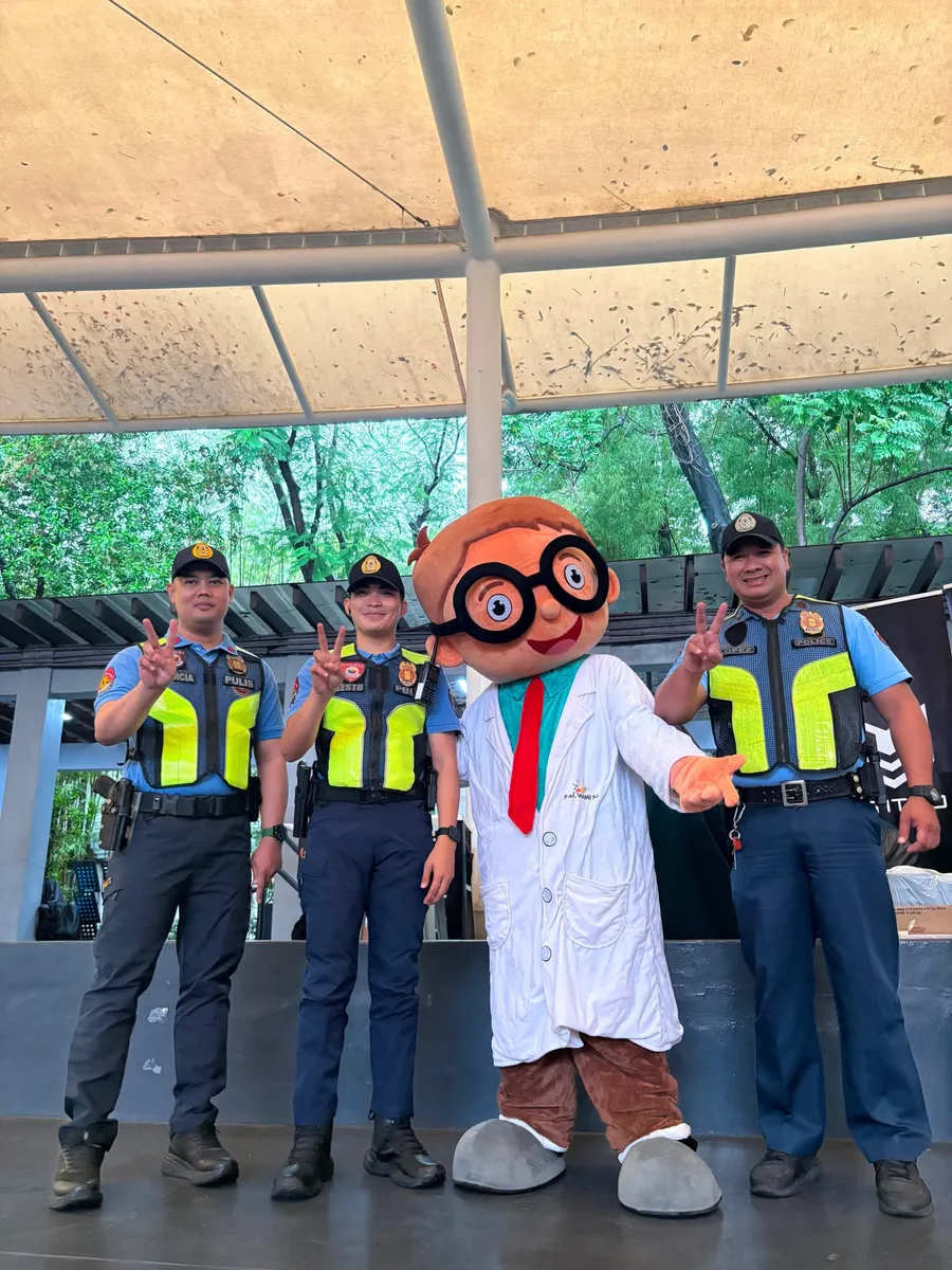 The WanderLab Scientist mascot with officers on duty at the venue
