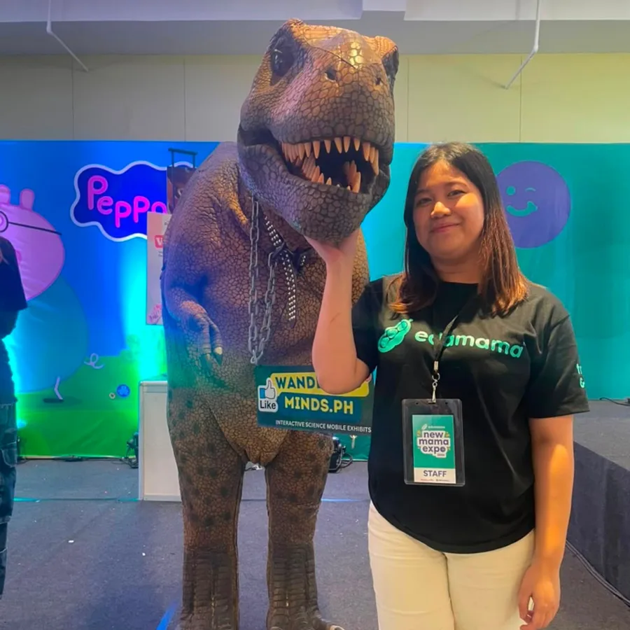 An EDAMAMA New Mama Expo 2026 staff member posing with the Wandering Minds Jurassic T-Rex mascot