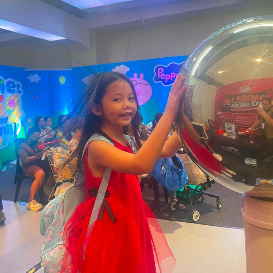 A young girl touching the Van de Graaff generator sphere, her hair standing on end from static electricity
